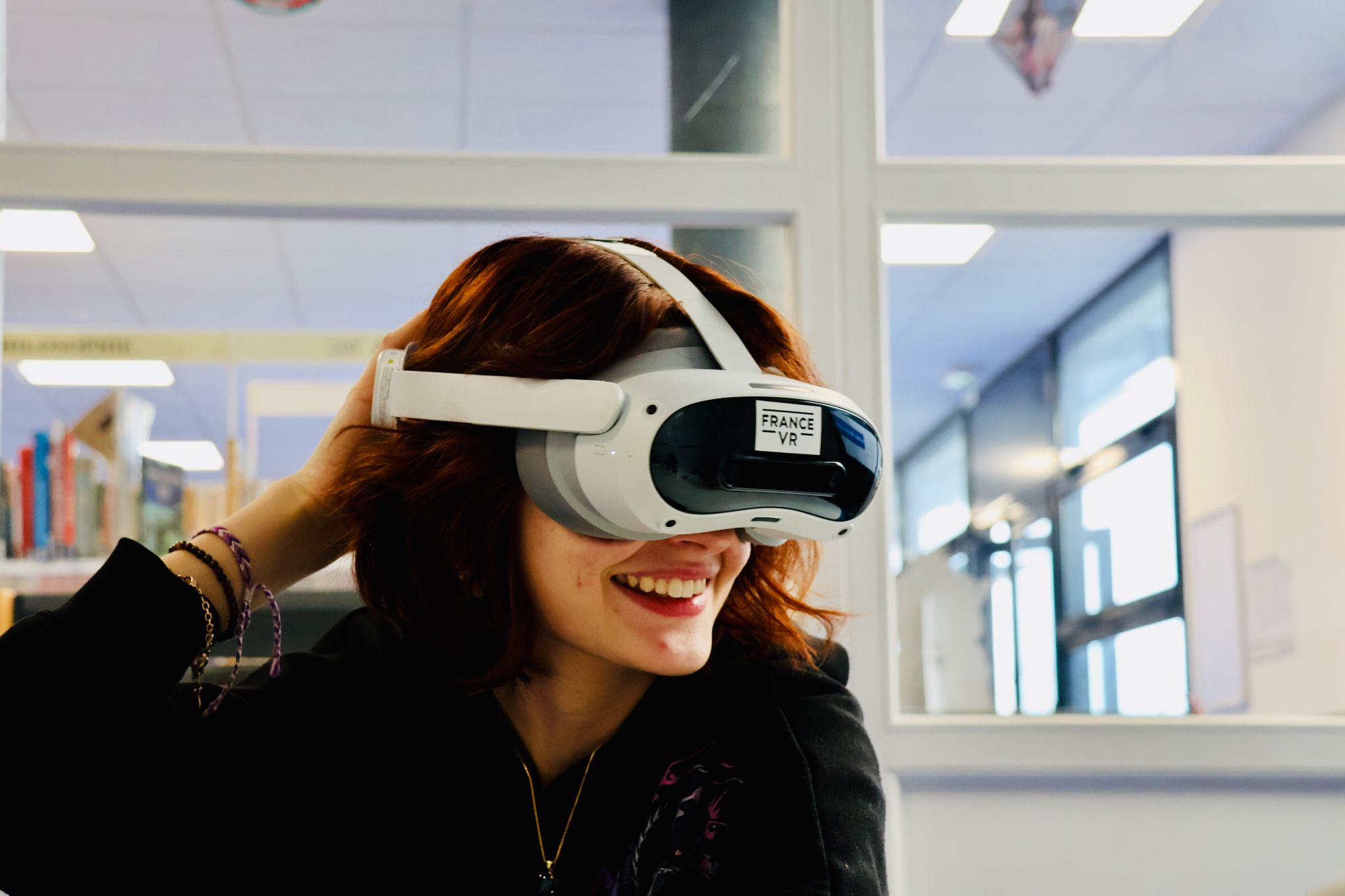 Jeune femme souriante portant un casque VR France VR dans une médiathèque