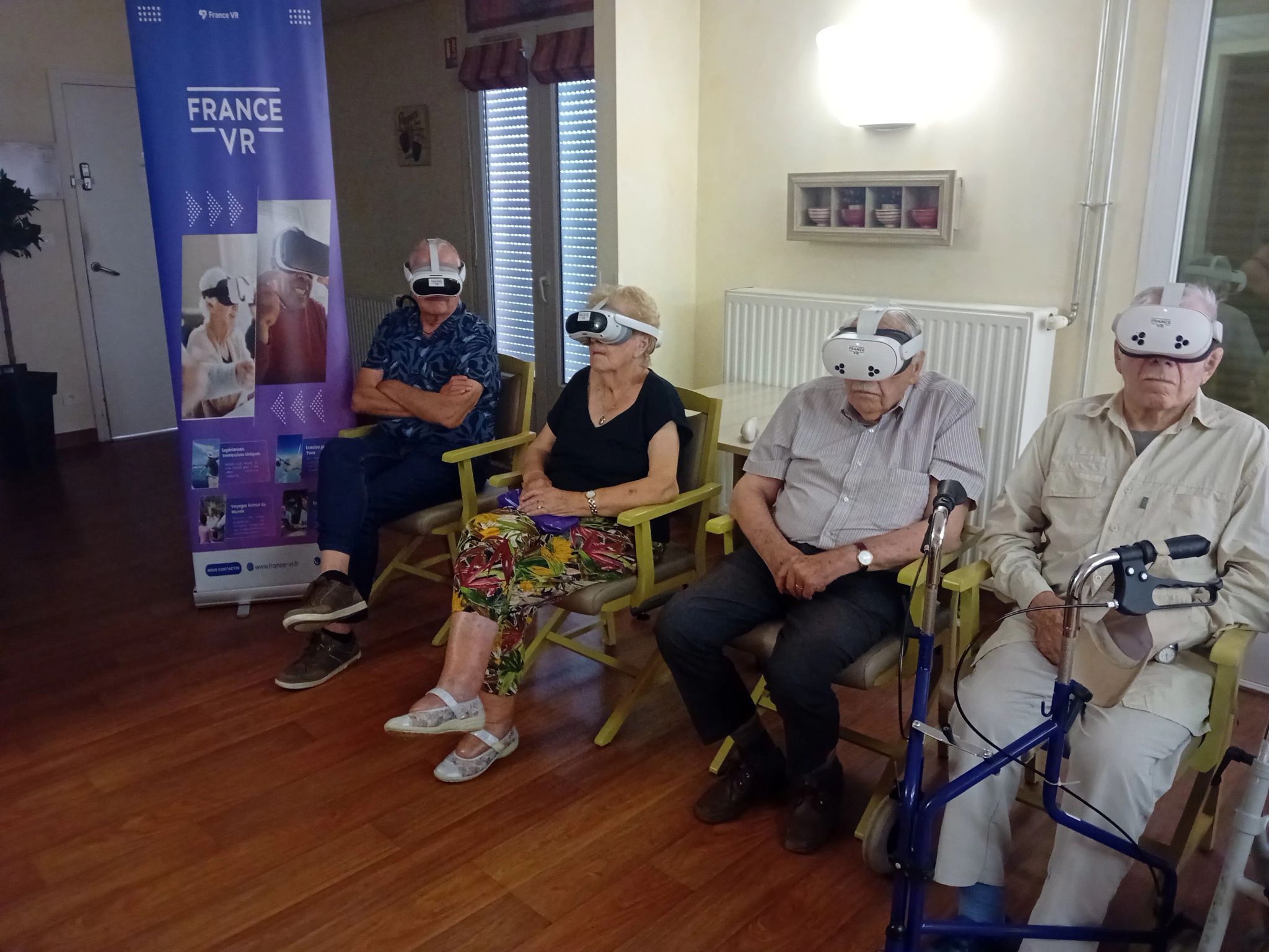 Quatre résidents d'un EHPAD portant des casques VR France VR assis dans un salon, banner France VR en arrière-plan